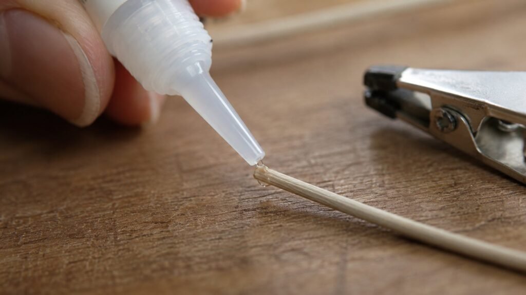 Aplicando adhesivo con un tubo sobre el extremo de una fibra de ratan sintetico