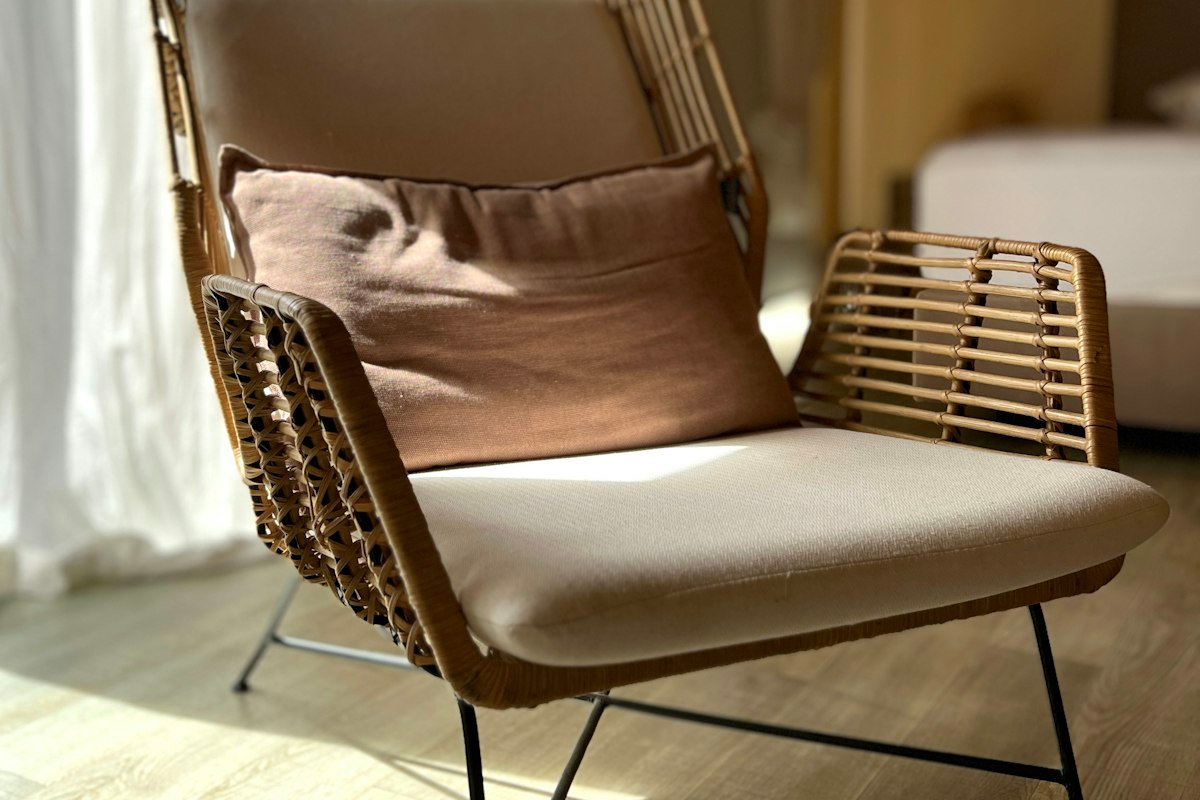 Sillón de ratán con cojín junto a una ventana