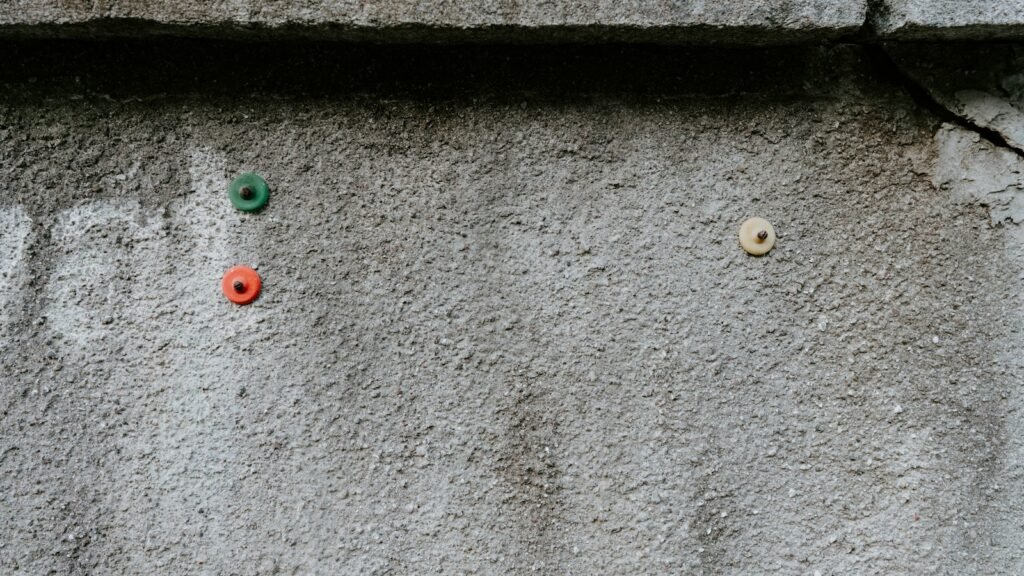 Tacos de colores clavados en una pared de hormigón