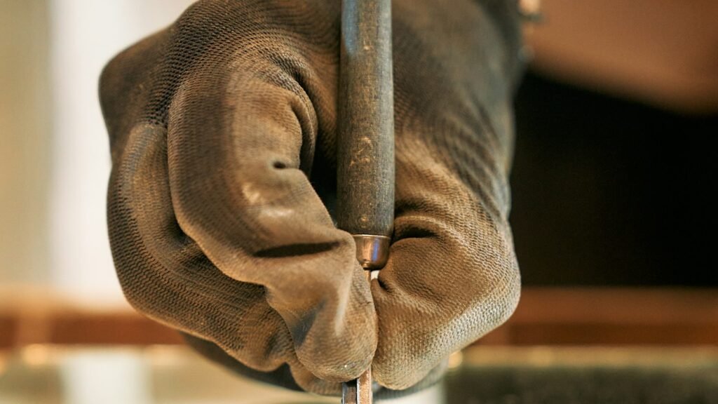 Mano con guante taladrando un cristal