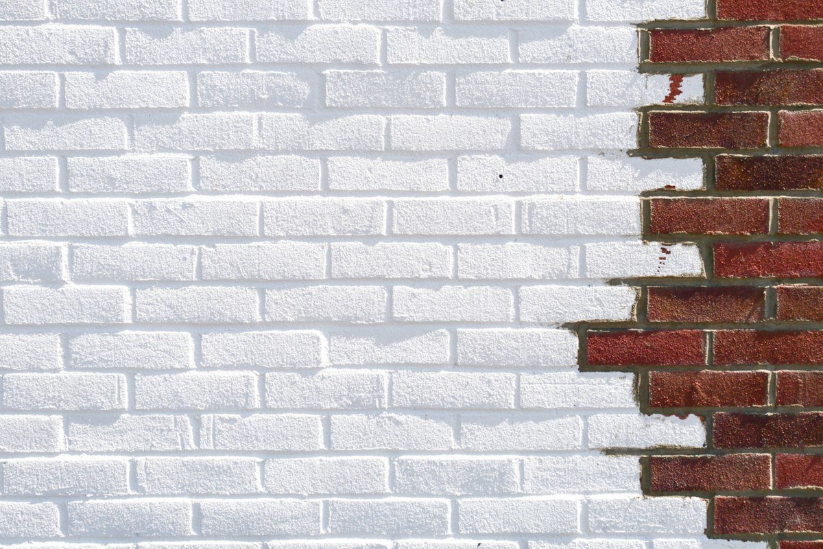 Pared de ladrillo pintada de blanco con parte del ladrillo a la vista